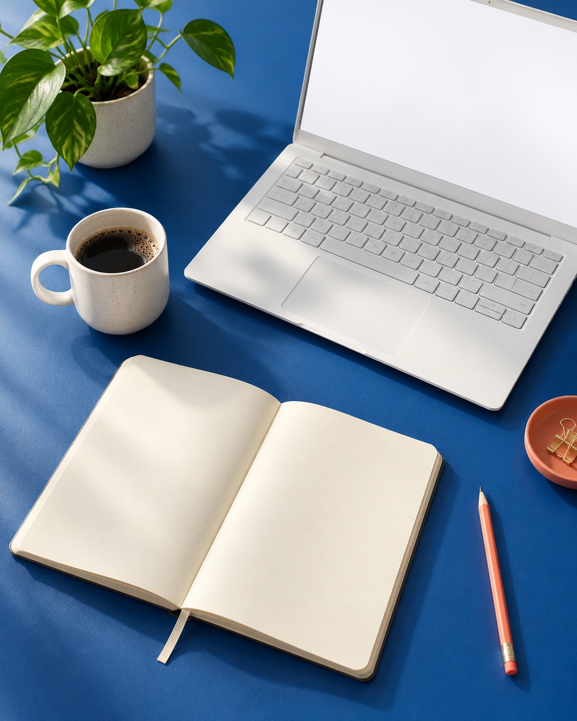 Cuaderno abierto y una computadora sobre un escritorio azul, un espacio para aprender